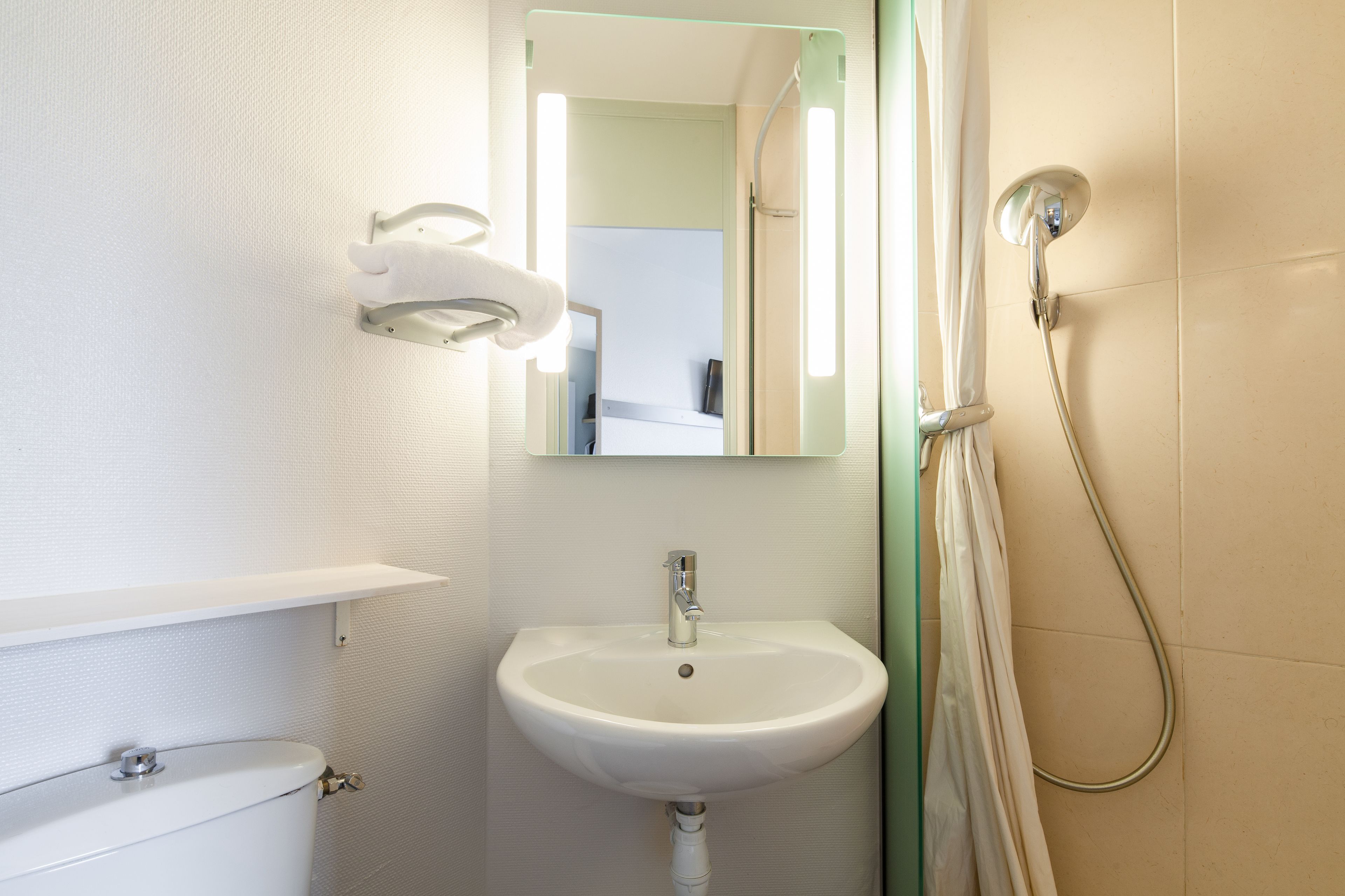 Een badkamer met een witte wastafel, een spiegel en een douche.