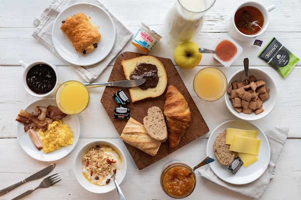 Una mesa de desayuno con diferentes alimentos y acompañamientos.