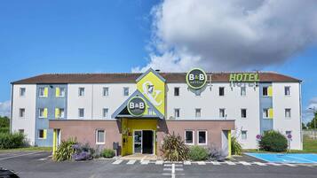 Stylish B&B Hotel with a flat roof and symmetrical facade, featuring multiple windows and a convenient parking space.