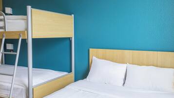 Een stapelbed met een houten hoofdbord en witte beddengoed, voor een wand in turquoise.
