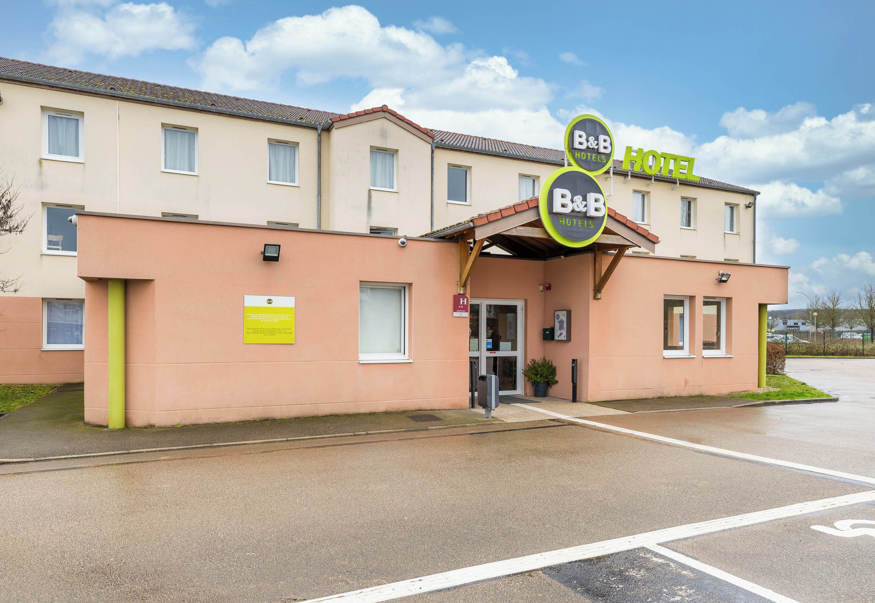 Un hotel tipo bed and breakfast con una fachada sencilla, un acceso cubierto y un estacionamiento.