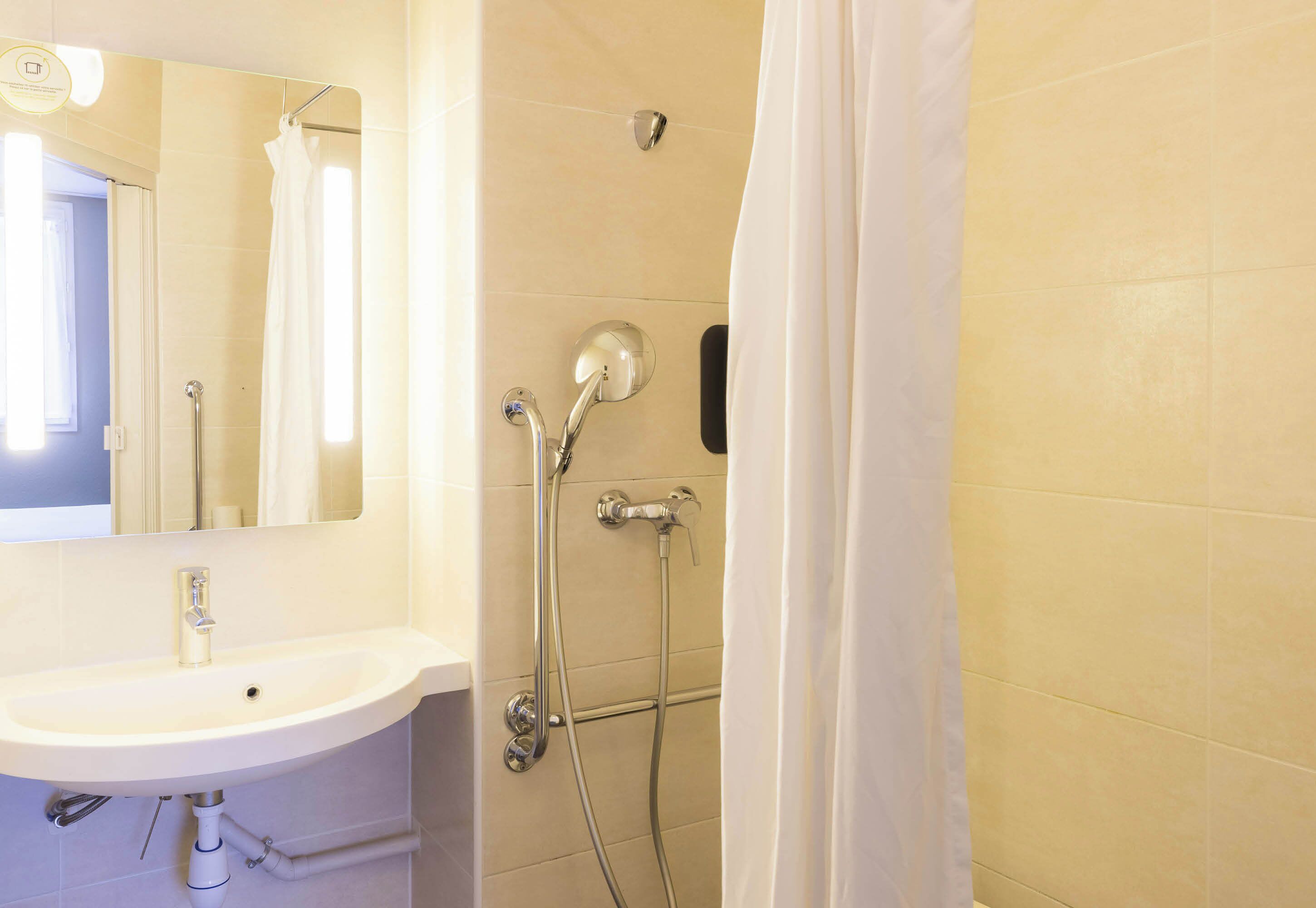 Baño con lavamanos, espejo, ducha y cortina.