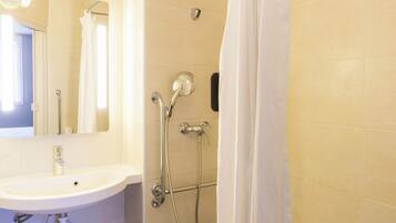Une salle de bain équipée d’un lavabo, d’un miroir, d’une douche et d’un rideau de douche.