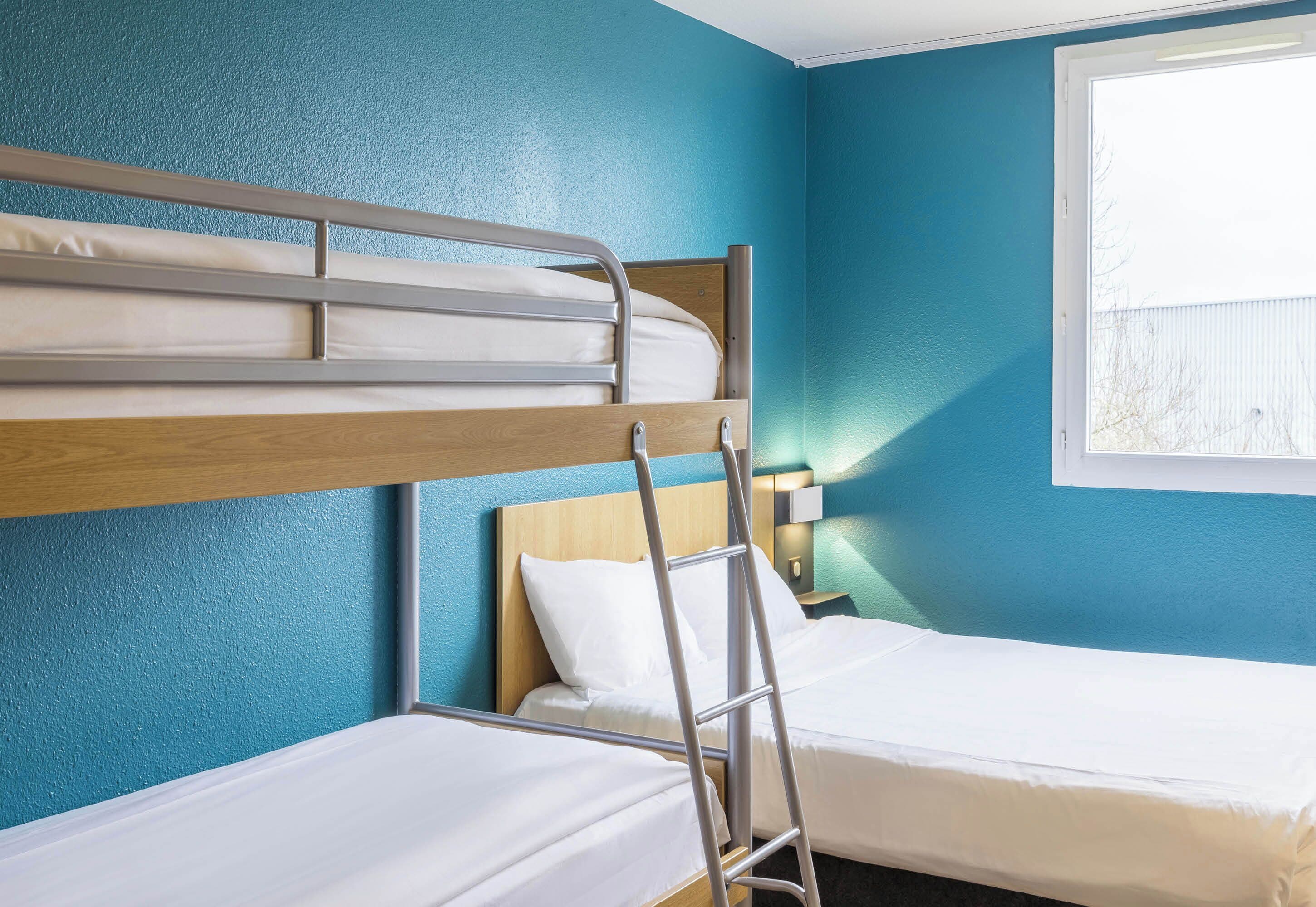 Habitación con literas, una mesita de noche con lámpara y ventana con vistas al exterior.