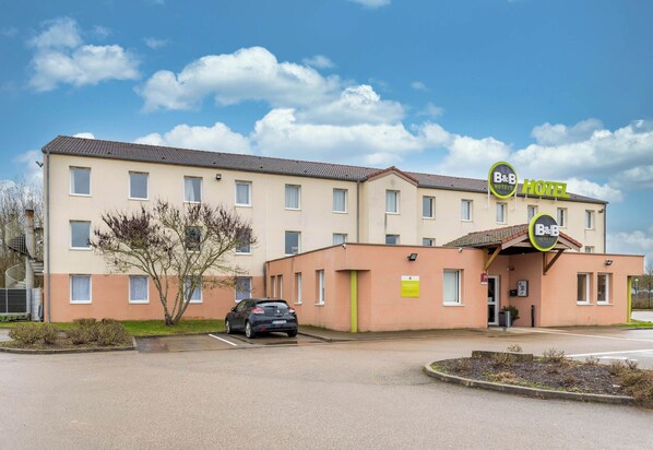 A B&B hotel with a parking lot, a car parked in front, and a clear sky. - B&B HOTEL Auxerre Monéteau (Moneteau)