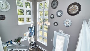Ein Zimmer mit Treppe, mehreren Fenstern und verschiedenen Wanduhren.
