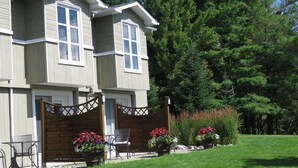 Ein zweistöckiges Haus mit überdachter Terrasse, Holzzaun und Rasen.