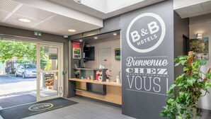 Een hotel receptie met een modern design, een receptiebalie, een digitaal scherm en een welkomstbord.