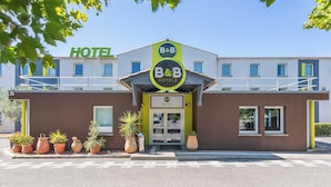 Een bed en breakfast hotel met een moderne gevel, een gastvrije entree en plantenbakken langs de stoep.