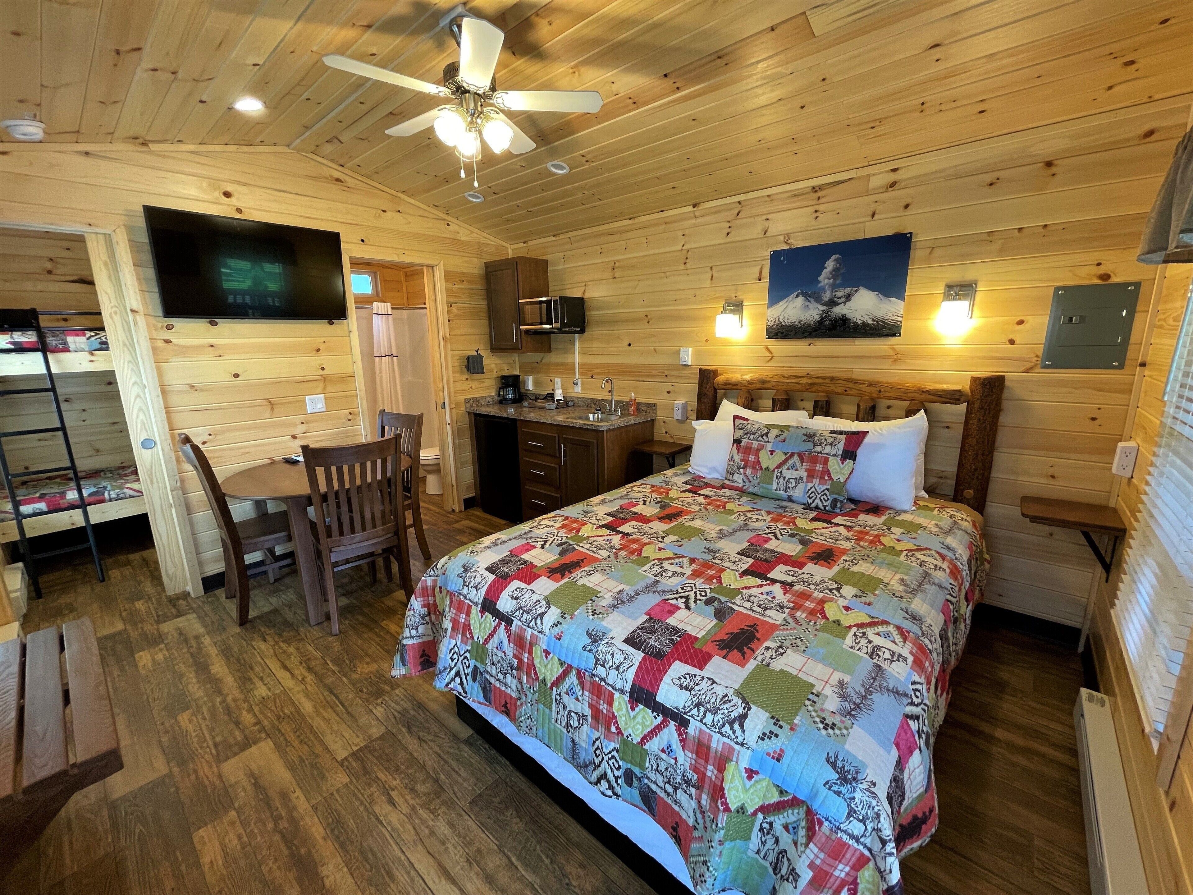 A cozy cabin-style room with a bed, a desk, and a chair.