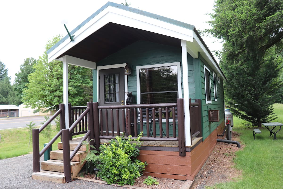 A small, single-story cabin with a porch and steps leading to a door.