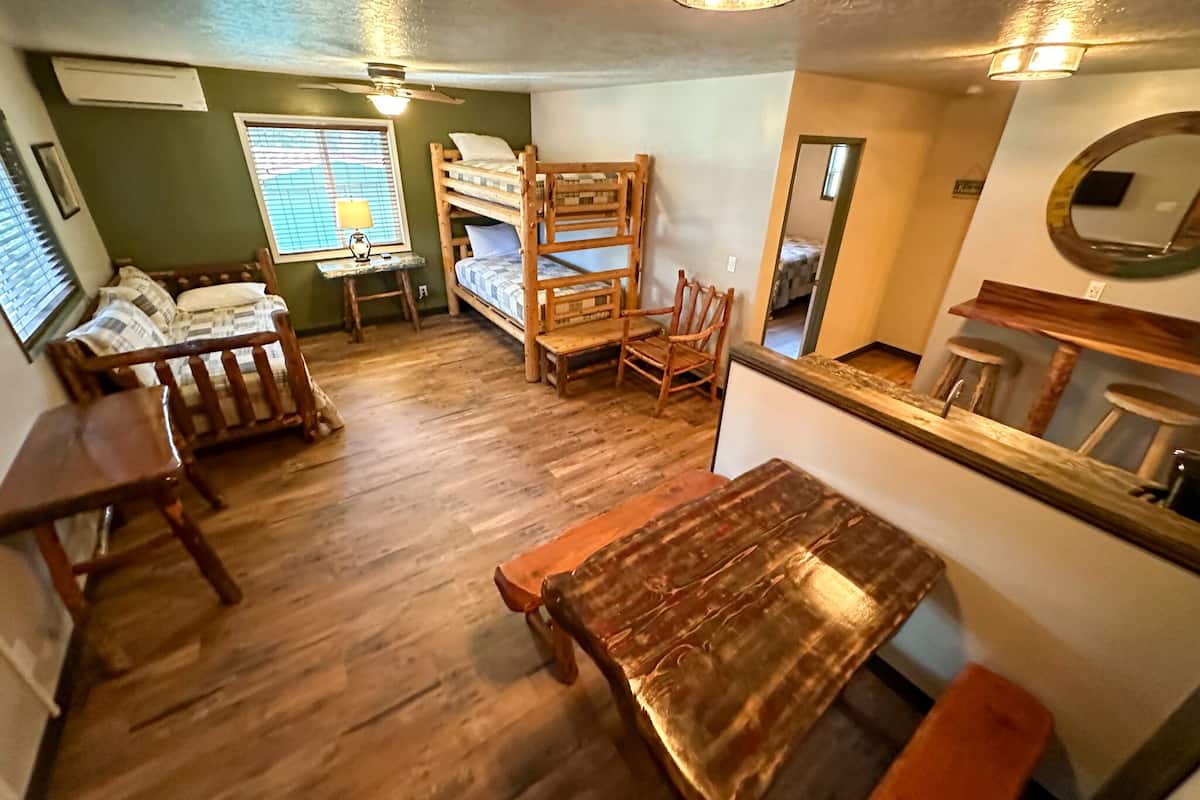 A compact room with bunk beds, a wooden table, and a small desk with a lamp.