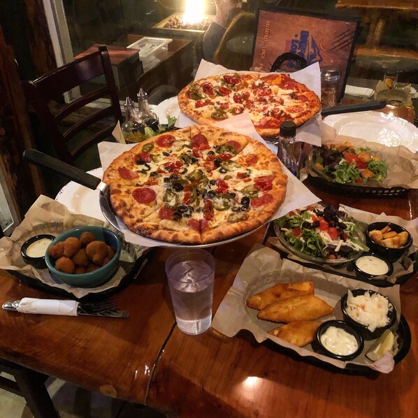 A dining table with two pizzas, a salad, and various side dishes. - Lone Fir Resort (Cougar)