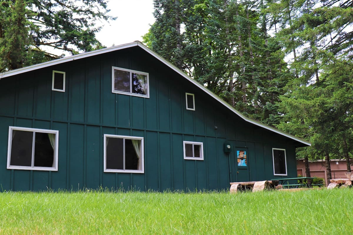 A green building with multiple windows and a covered porch area.