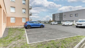 Un estacionamiento con varios coches, un edificio con muchas ventanas y un cielo parcialmente nublado.
