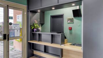 A reception area with a wooden counter, a black door, and a green wall.