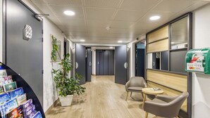 Un área de recepción moderna con mostrador, zona de estar y una planta.