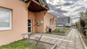 Un hotel tipo bed and breakfast con un letrero, una pequeña zona de estar al aire libre y un camino pavimentado.