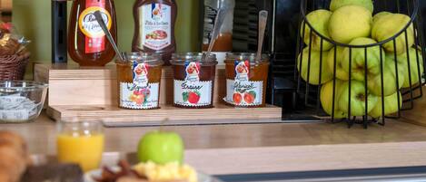 A breakfast setup with bread, honey jars, apples, and a juice glass.