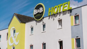 A B&B hotel with a distinctive yellow and white facade, multiple windows, and a clear blue sky.