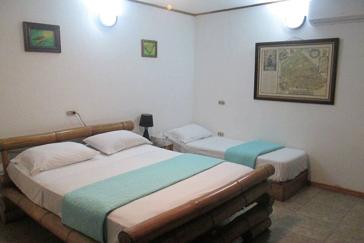 Una habitación con dos camas, una mesita de noche, una lámpara y un mapa enmarcado en la pared.