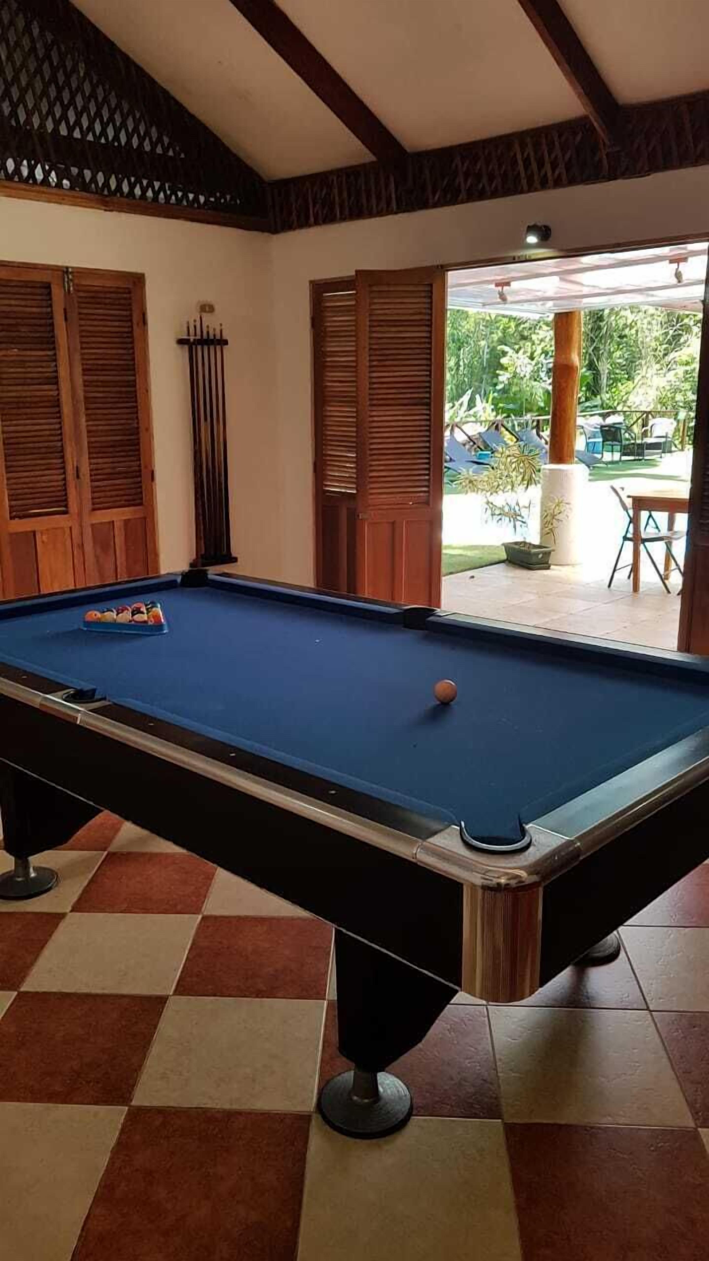 Uma mesa de bilhar com bolas, armários de madeira e piso xadrez.