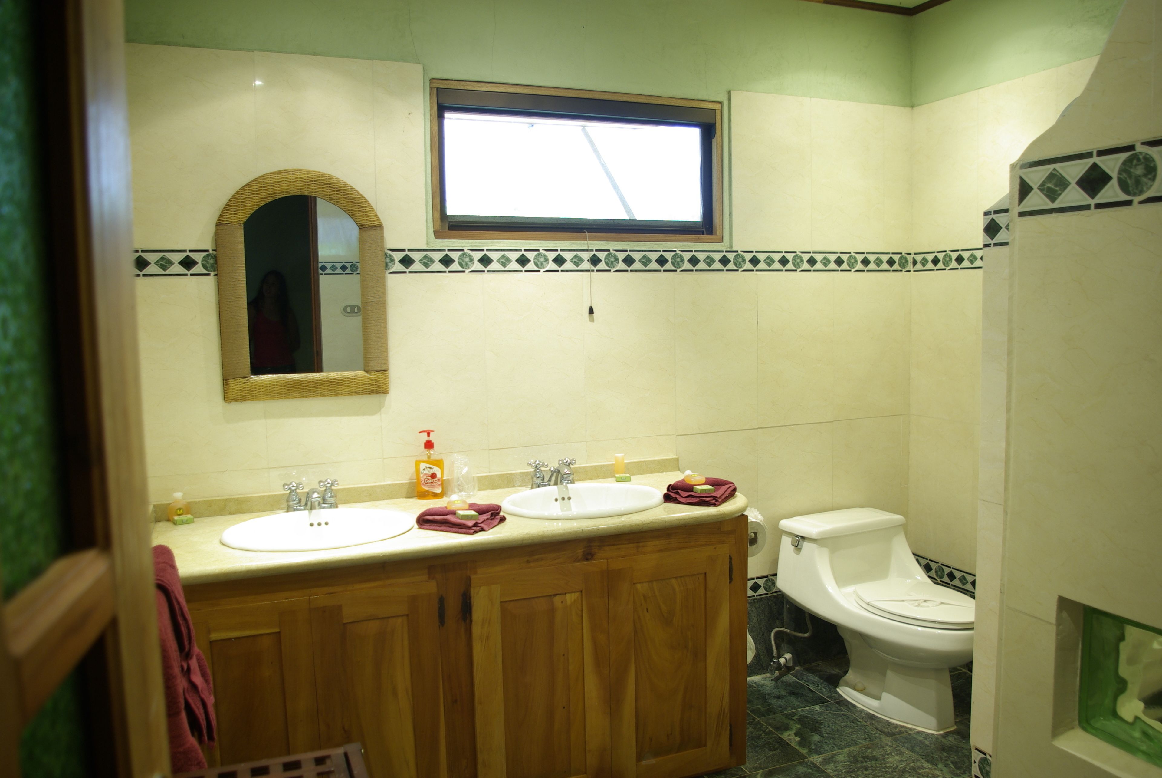 Un baño con dos lavamanos, un inodoro y un ventanal.