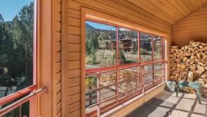 A wooden cabin with a large window overlooking a mountainous area.