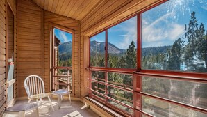A wooden cabin with large windows offering a mountain view.