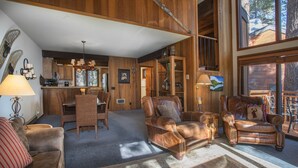 A spacious living area with leather sofas, a dining table, and a kitchen in the background.