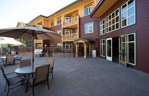 A multi-story building with a patio area featuring outdoor seating and a barbecue grill.