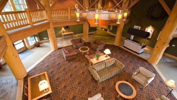 A spacious loft-style room with high ceilings, exposed wooden beams, and a large open area with a fireplace. There are multiple seating options including sofas and chairs, and a dining table. - Sunstone Lodge by 101 Great Escapes (Mammoth Lakes)
