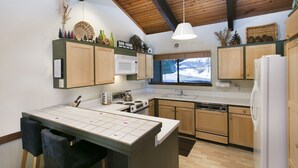 A modern kitchen with wooden cabinets, a central island, and a window with a view of the outdoors. - Mammoth Point by 101 Great Escapes (Mammoth Lakes)