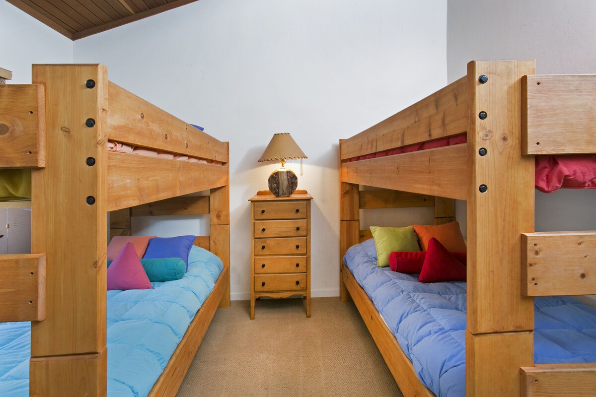 Una habitación con dos literas, un aparador de madera y una lámpara.