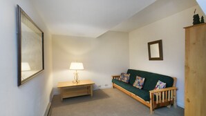 A cozy living room with a green sofa, a wooden bench, a lamp, and a mirror on the wall. - Mammoth Point by 101 Great Escapes (Mammoth Lakes)