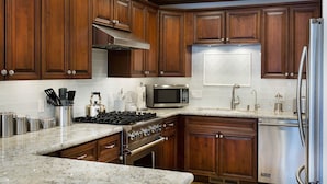 Una cocina con armarios de madera, un refrigerador de acero inoxidable, un microondas y una estufa.