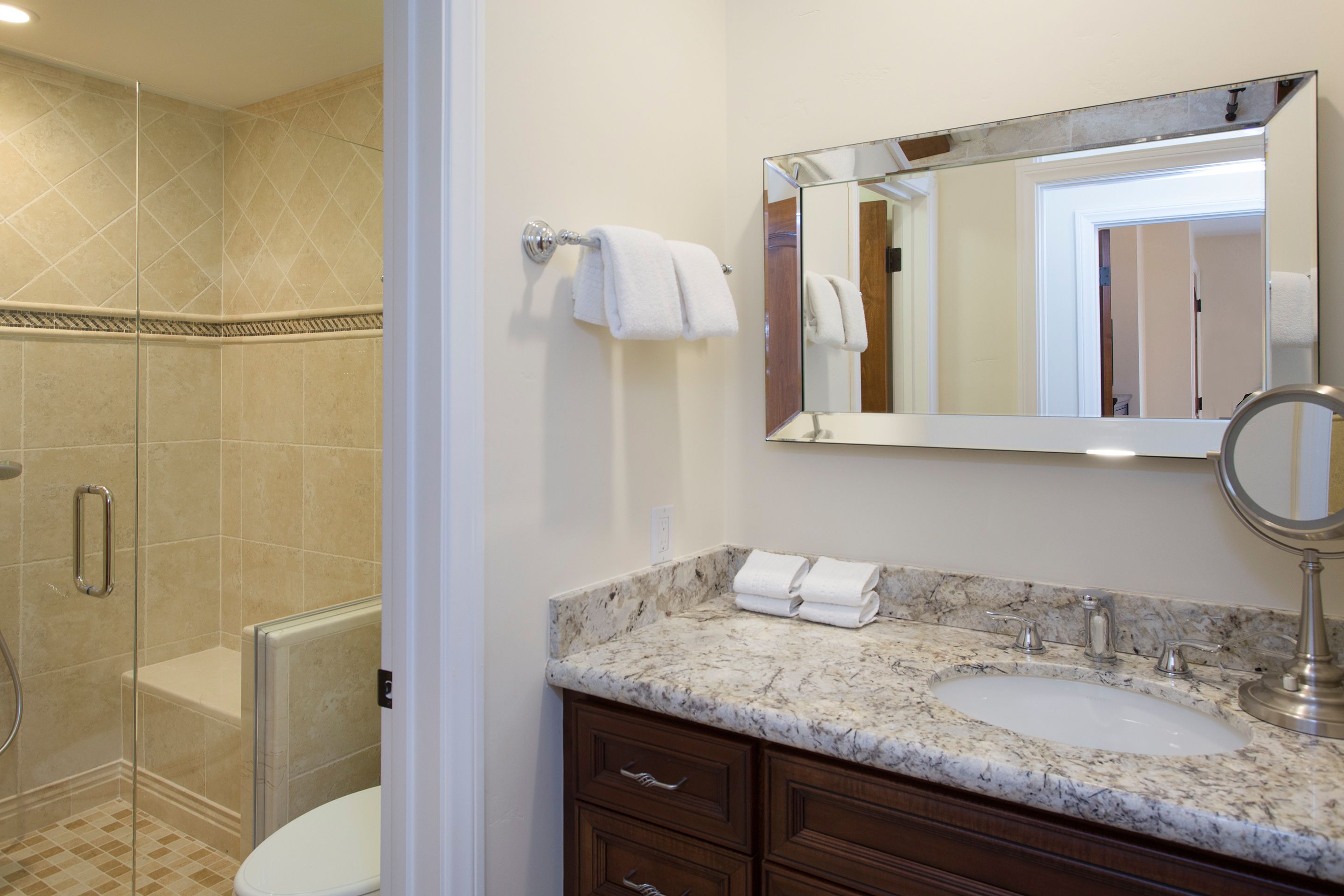 A bathroom with a marble sink, a large mirror, and a glass shower enclosure.