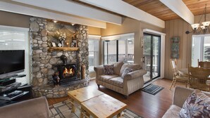 Una sala de estar acogedora con chimenea de piedra, asientos cómodos y un televisor.