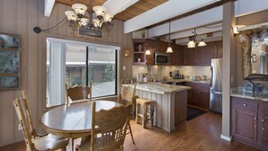 Una cocina con armarios de madera, una isla central y un comedor con una mesa redonda y sillas.