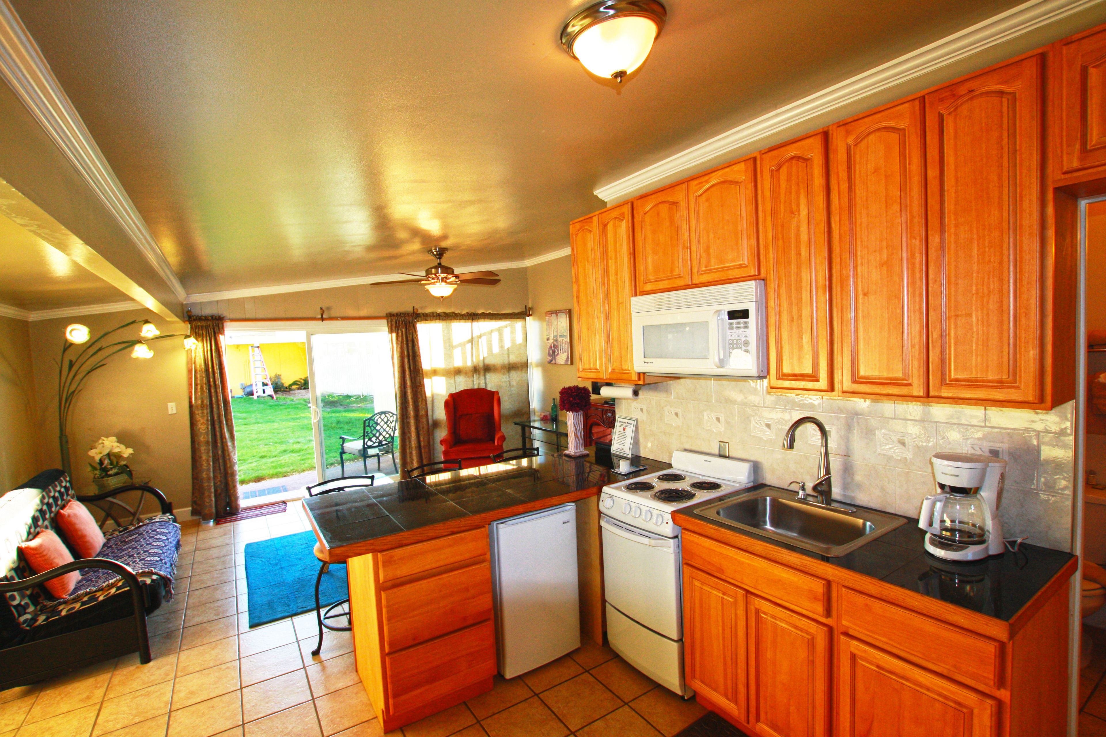 A compact kitchen with wooden cabinets, a microwave, a stove, and a refrigerator.