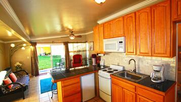 A compact kitchen with wooden cabinets, a microwave, a stove, and a refrigerator.