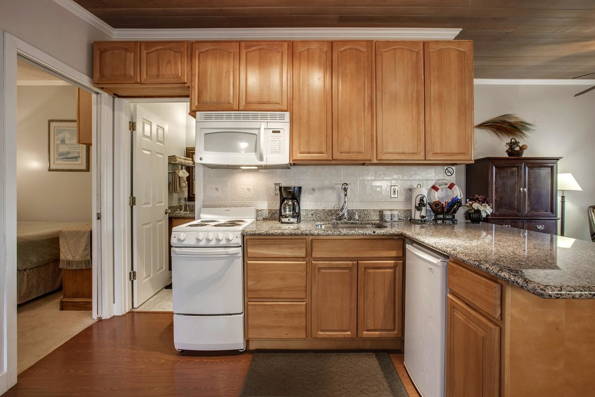 A kitchen with wooden cabinets, a white stove, a microwave, and granite countertops.