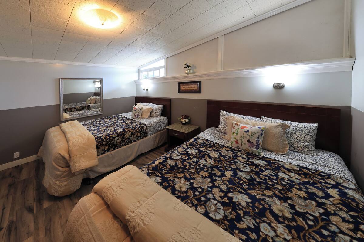 A bedroom with two beds, a nightstand, a mirror, and a ceiling light.
