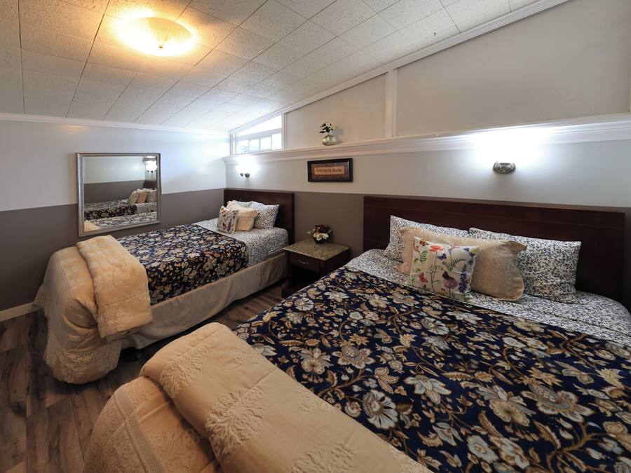 A bedroom with two beds, a nightstand, a mirror, and a ceiling light.
