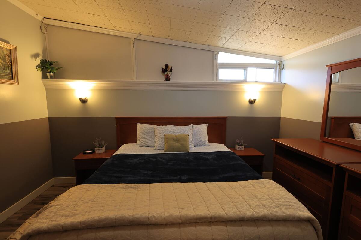A neatly arranged bedroom with a large bed, bedside tables, a dresser, and a mirror.