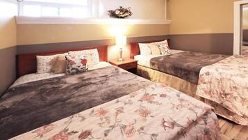 Habitación de hotel con dos camas, una mesita de noche con lámpara y un adorno floral en la pared.