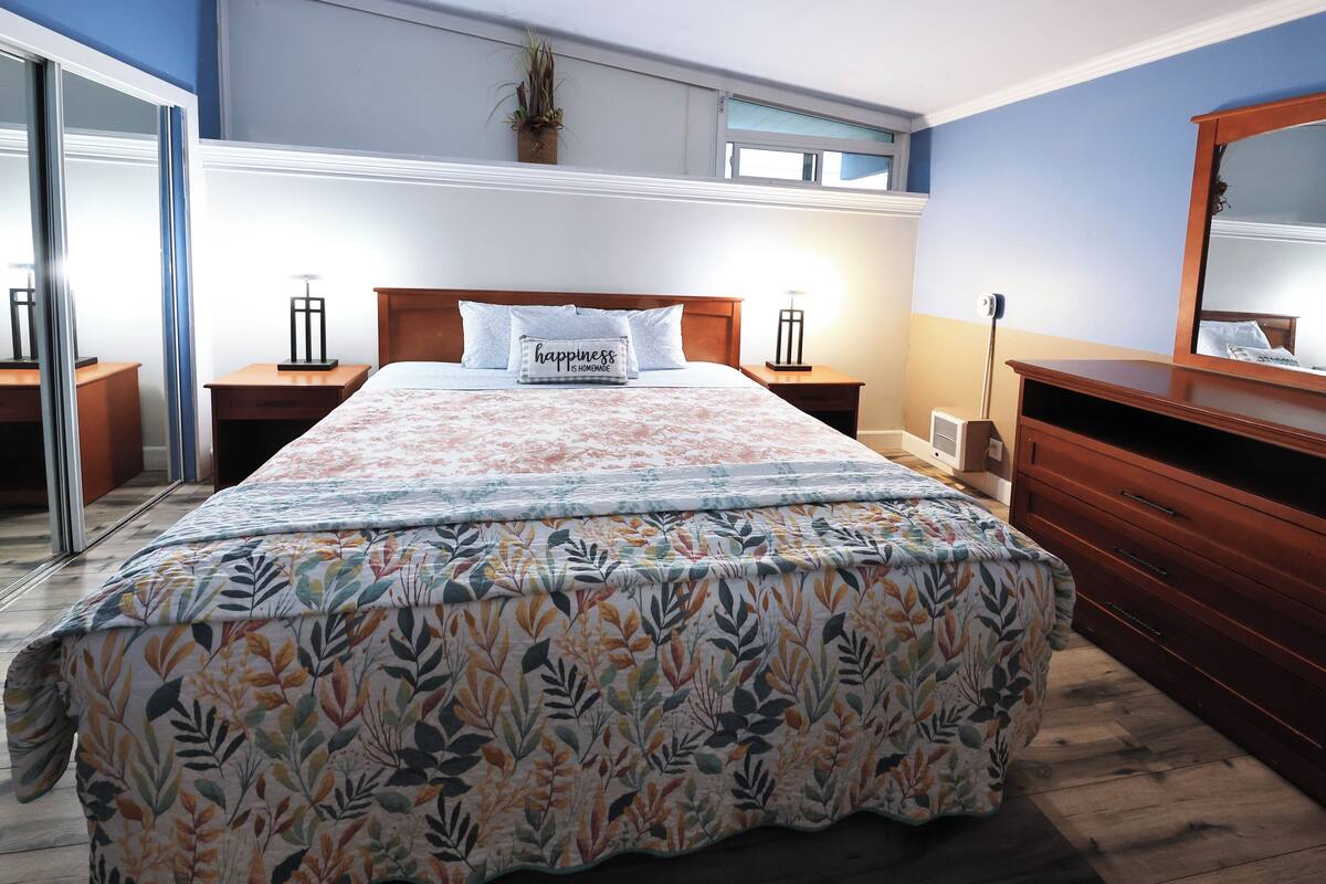 A neatly made bed with floral bedding, a wooden headboard, and a bedside table with a lamp.