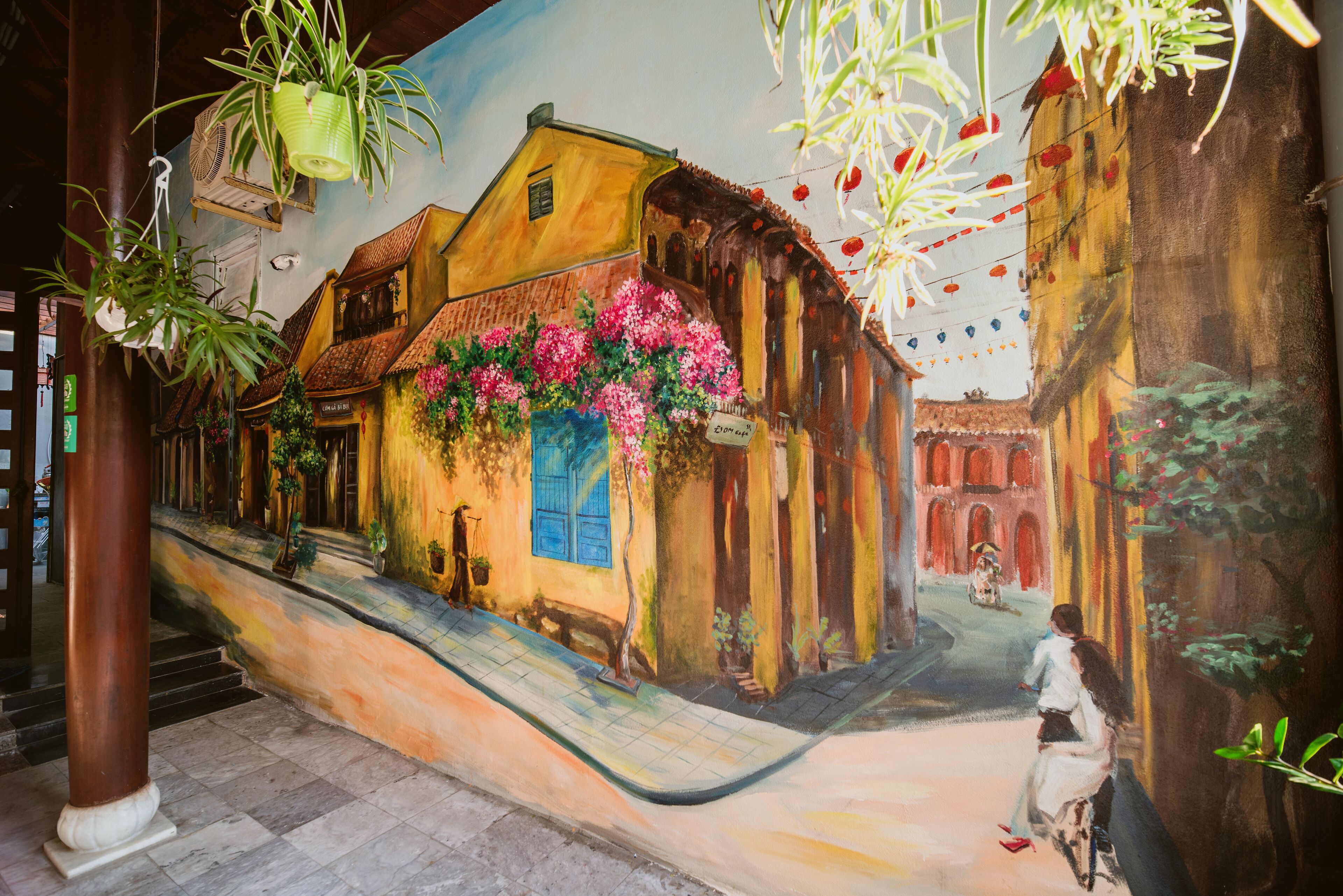 A mural of a street scene with buildings, a staircase, and a person riding a bicycle.