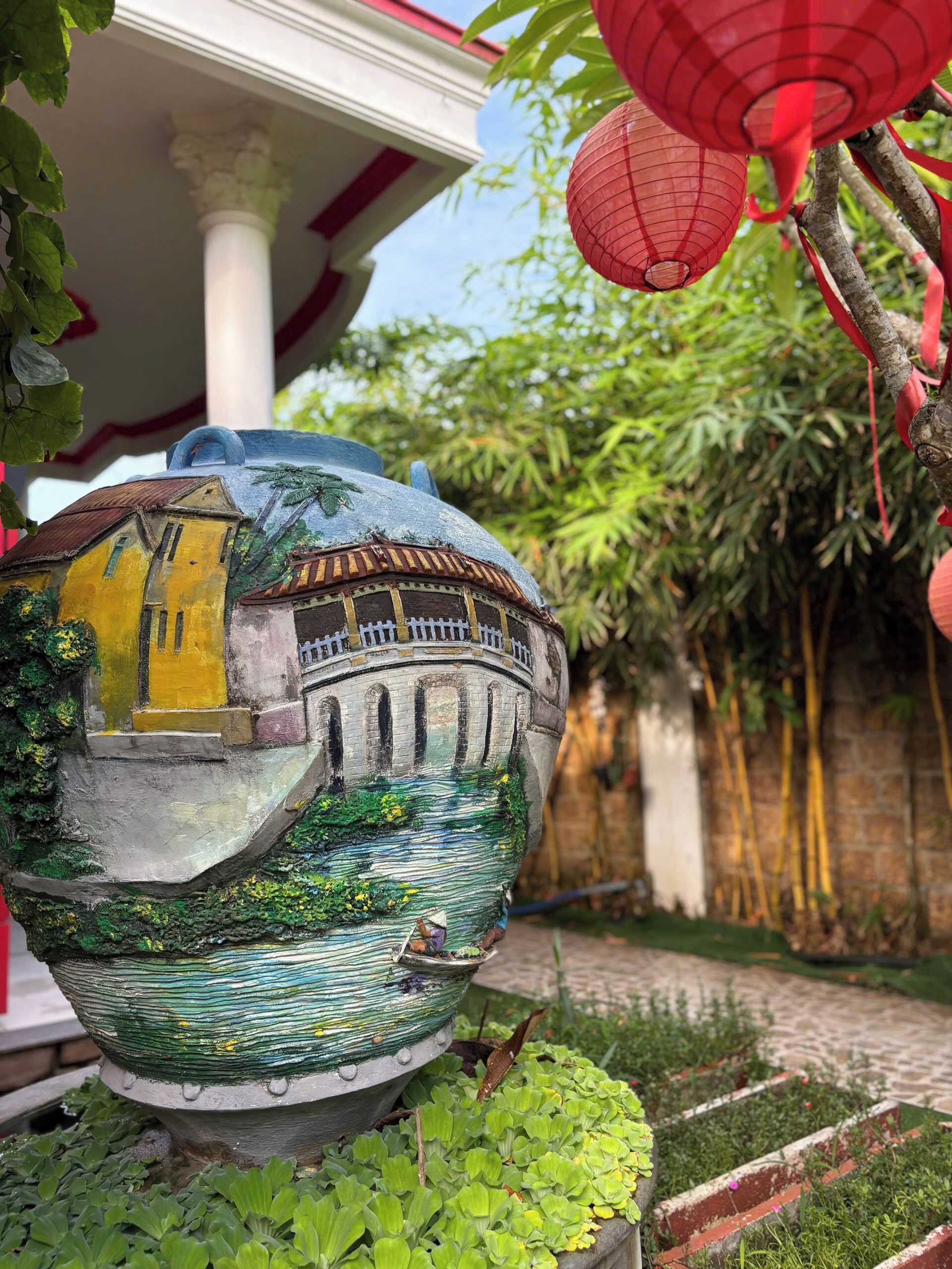 A decorative ceramic pot with a painted scene, placed outdoors with greenery around.