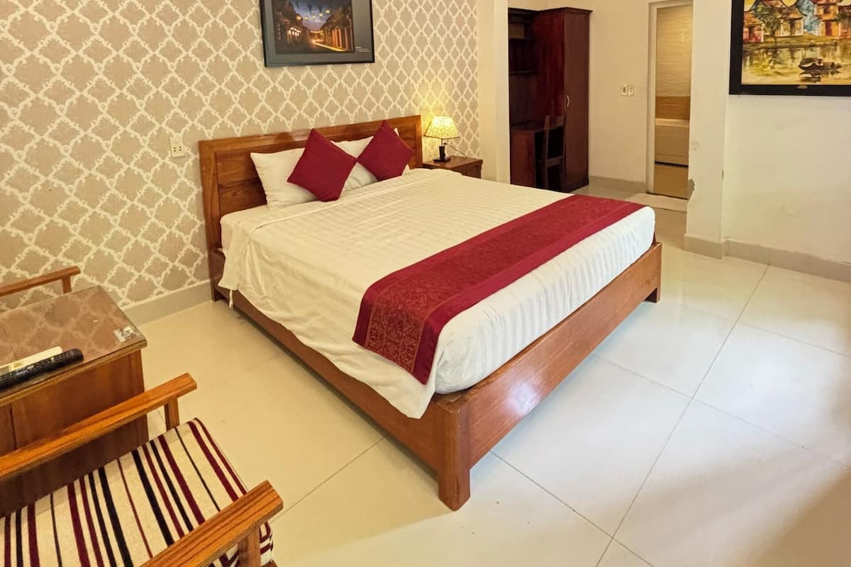 A neatly arranged bedroom with a wooden bed, a bedside table, a chair, and a wall-mounted picture.